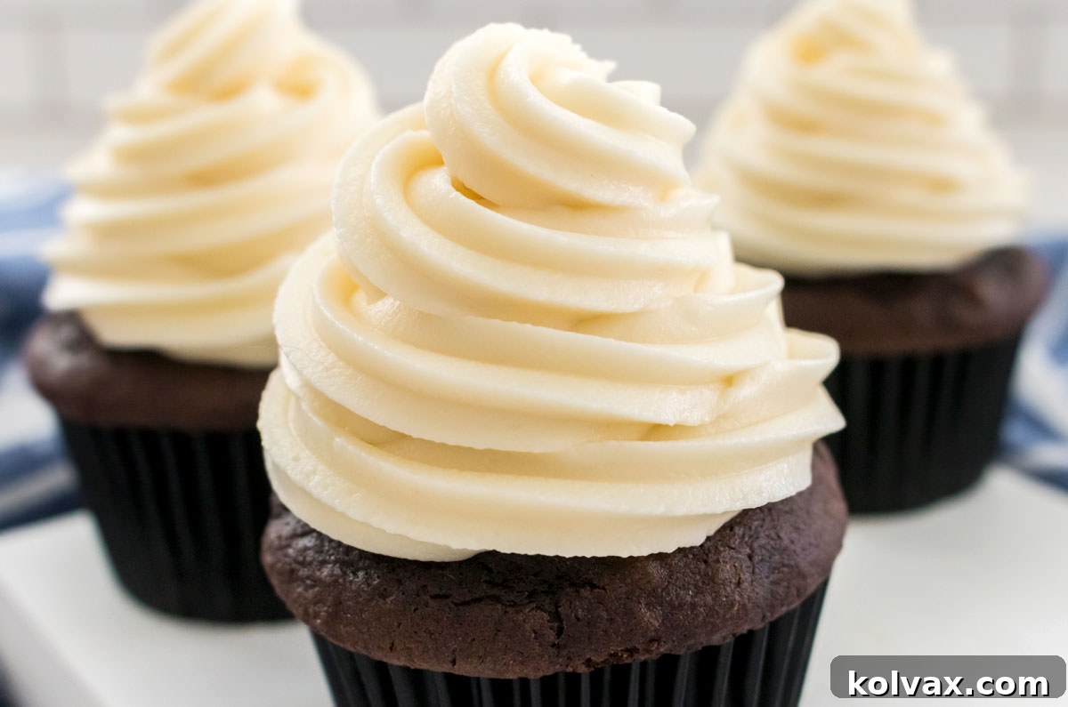 Three chocolate cupcakes sitting on a white board frosted with swirls of The Best Cream Cheese Frosting.