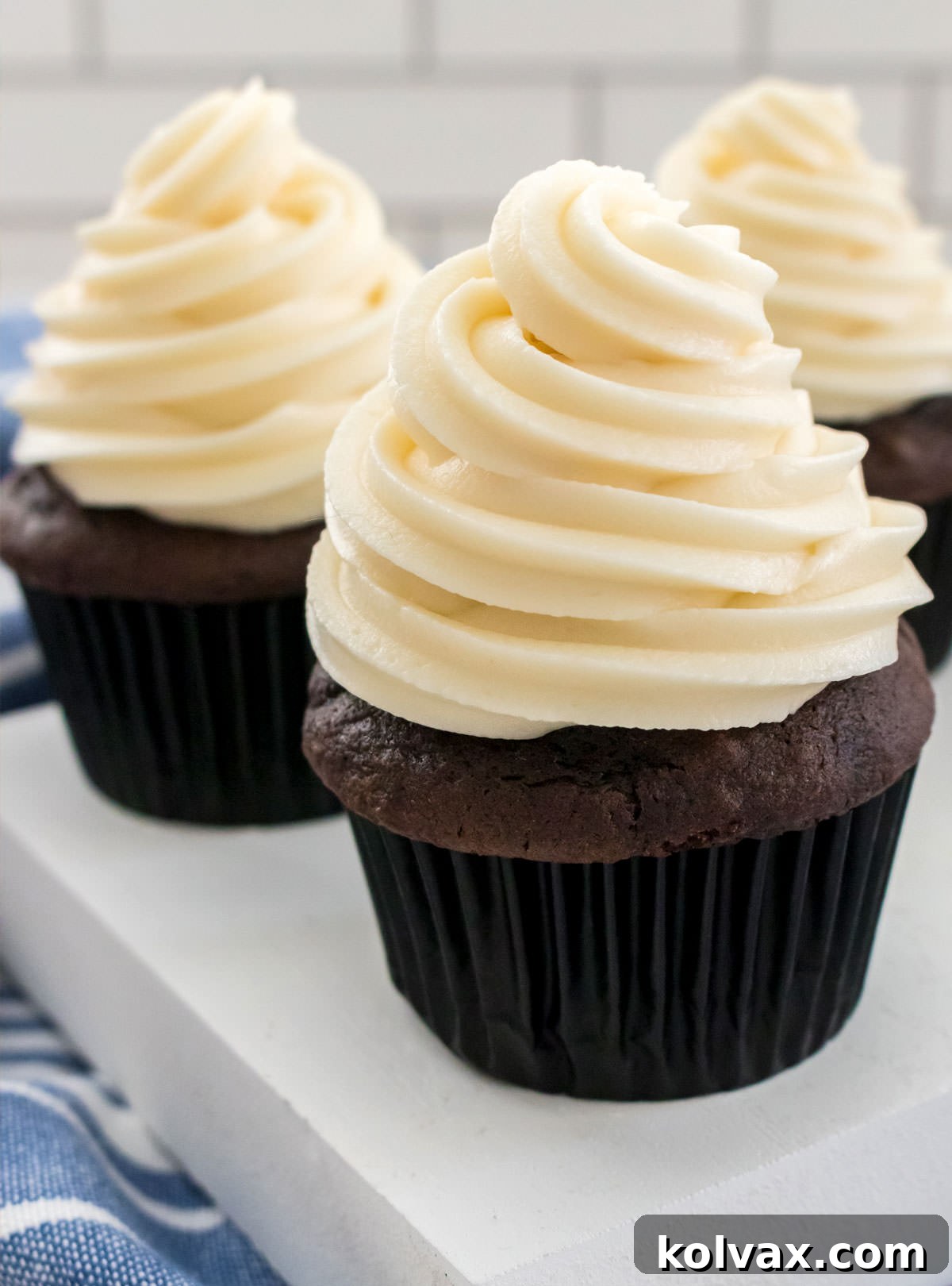 Closeup on three chocolate cupcakes topped with The Best Cream Cheese Frosting.