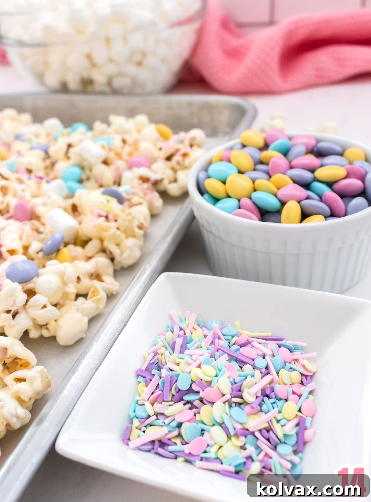 A close-up of colorful candy mix-ins, including pastel sprinkles and Easter M&M's, scattered on the marshmallow popcorn.