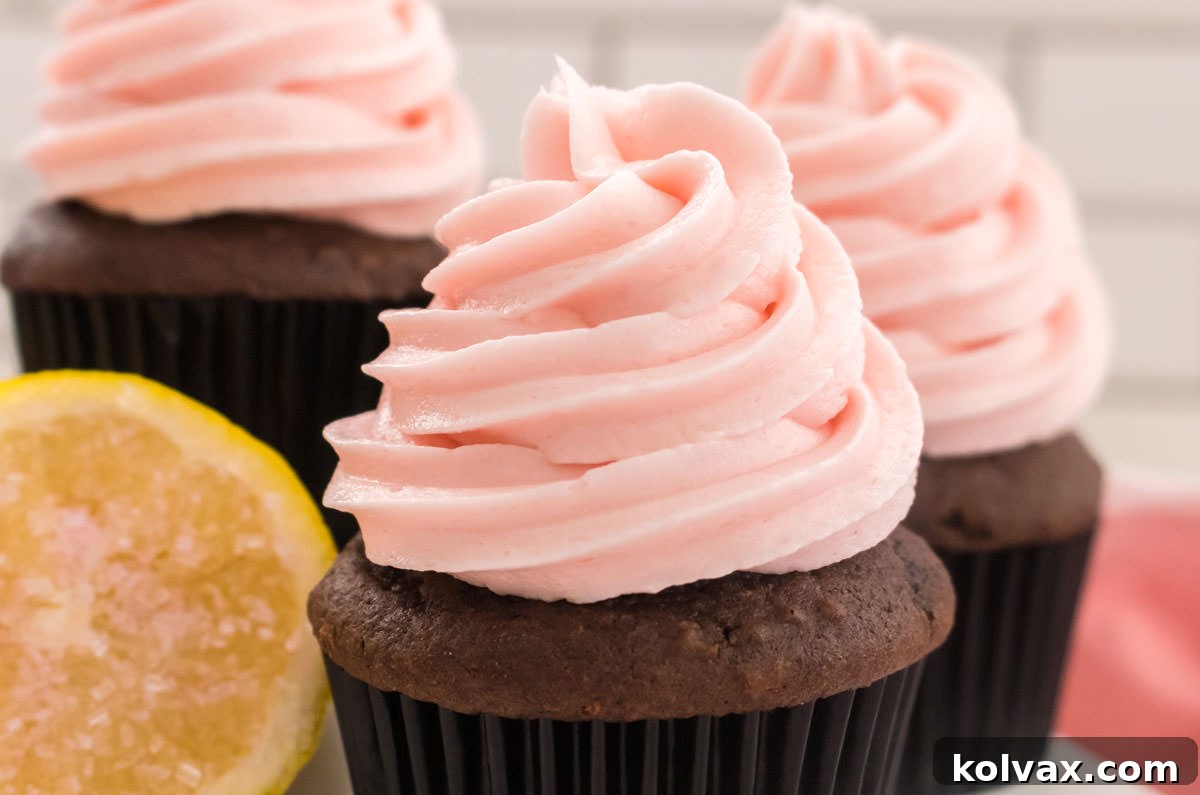 Three chocolate cupcakes elegantly frosted with homemade Pink Lemonade Frosting, garnished with lemon zest, ready for a spring or summer gathering.