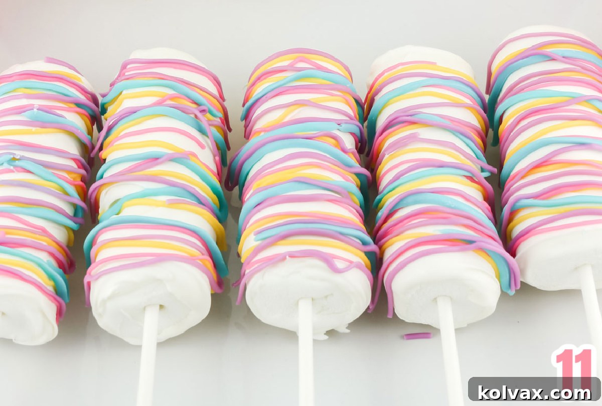 Close up on five beautifully decorated Celebration Marshmallow Pops laying on a white serving platter, showcasing their colorful drizzles.