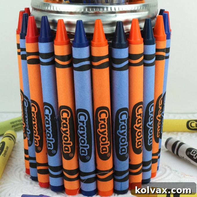 Securing the first crayon to a Mason jar with hot glue for a teacher gift