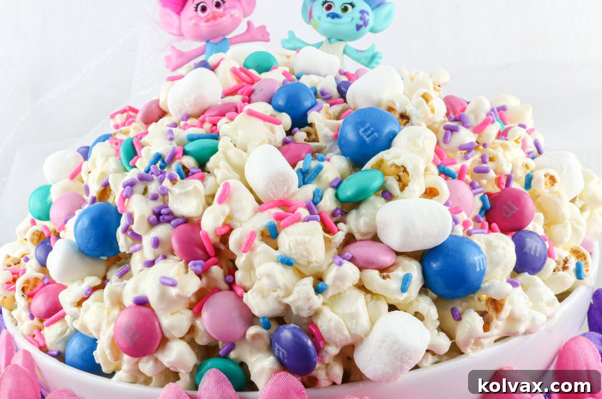 Closeup on a white serving bowl filled with Trolls Popcorn with two Trolls on the top of the bowl.