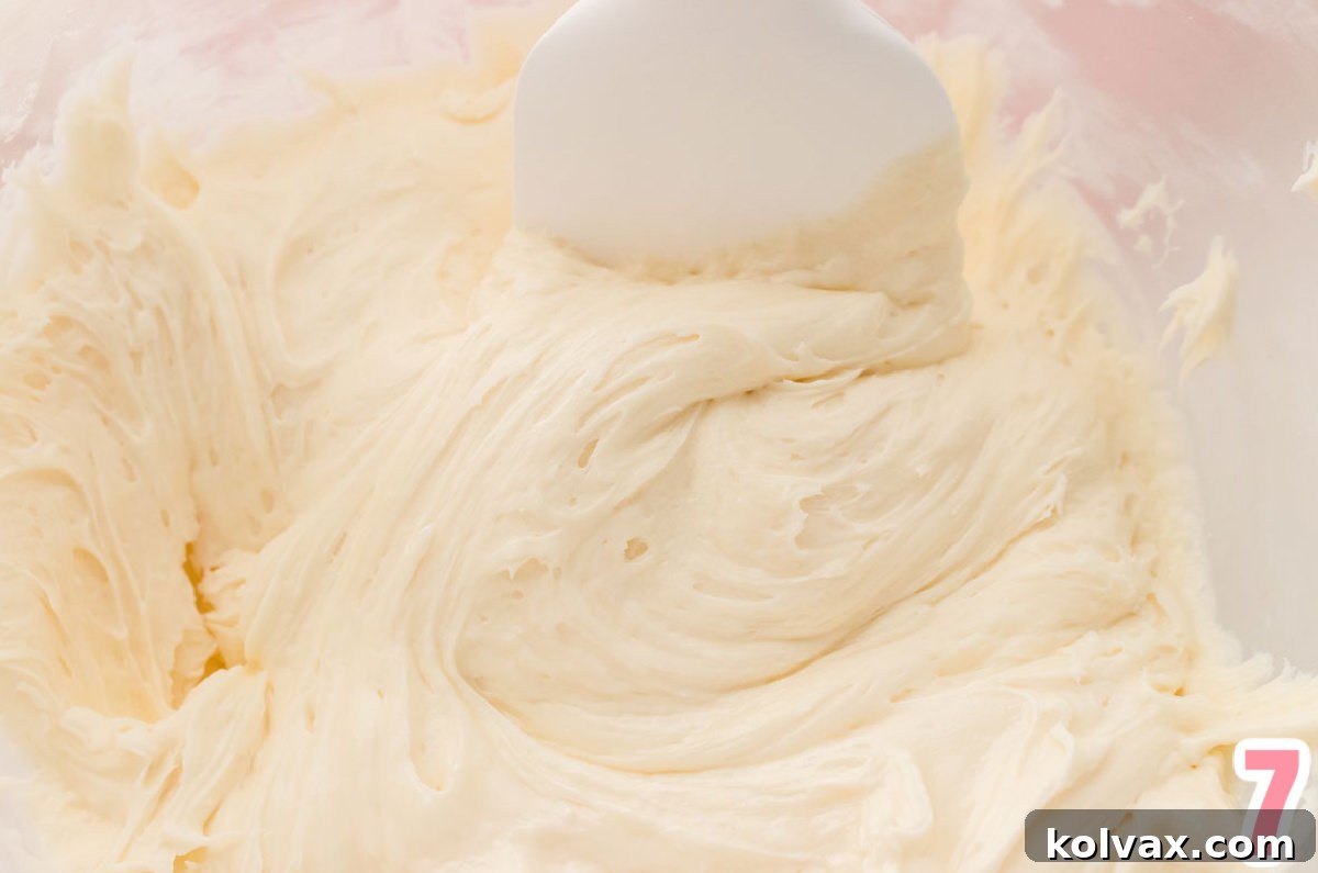 Closeup on a glass bowl filled with a batch of The Best Marshmallow Buttercream Frosting and a white spatula.