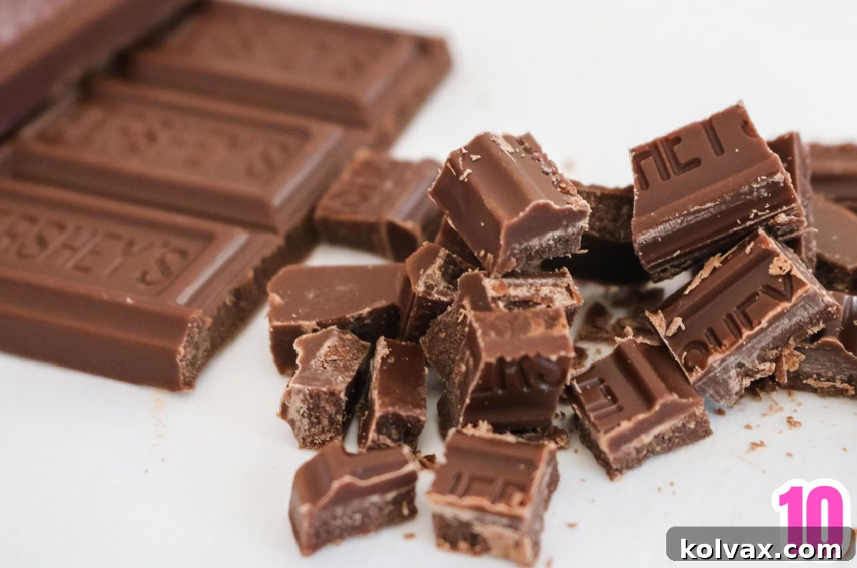 Closeup on a Hershey Chocolate Bar partly chopped into pieces on a white table, prepared for adding to the s'more pie filling.