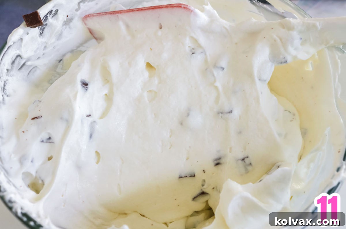 Glass mixing bowl filled with the fluffy, creamy marshmallow and Cool Whip filling for the S'more Pie, before the chocolate is added.