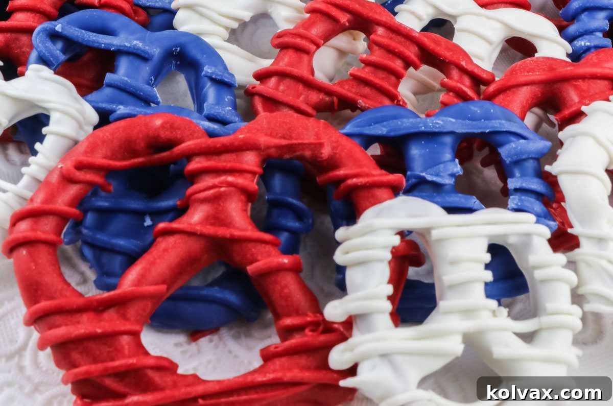 Closeup on a group of candy-coated Patriotic Pretzels in red white and blue sitting on a white surface, showcasing their vibrant colors and appealing texture.