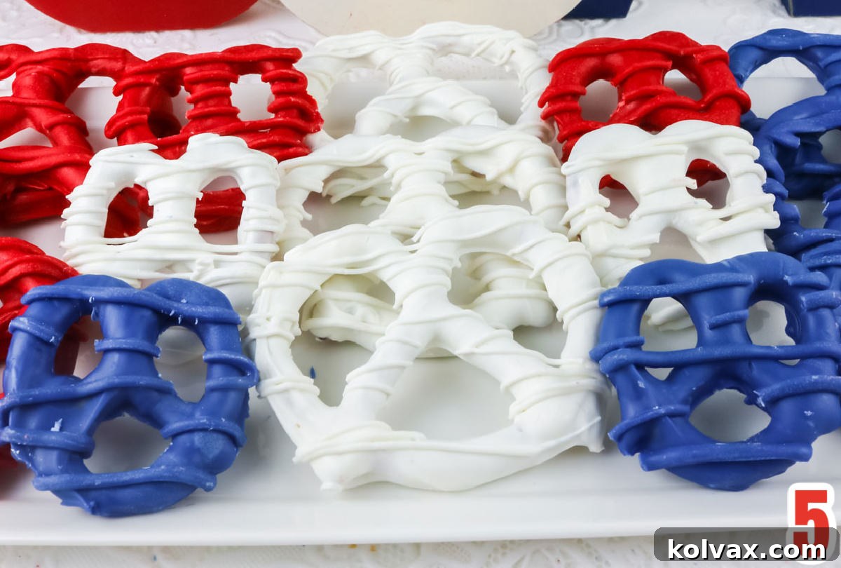 Close up of Red White and Blue Patriotic Chocolate Covered Pretzels laying on a white serving platter on a white table, highlighting their vibrant appeal.