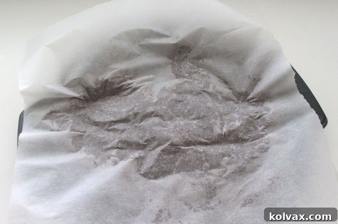 Pressing cookie dough with parchment paper in a pizza pan