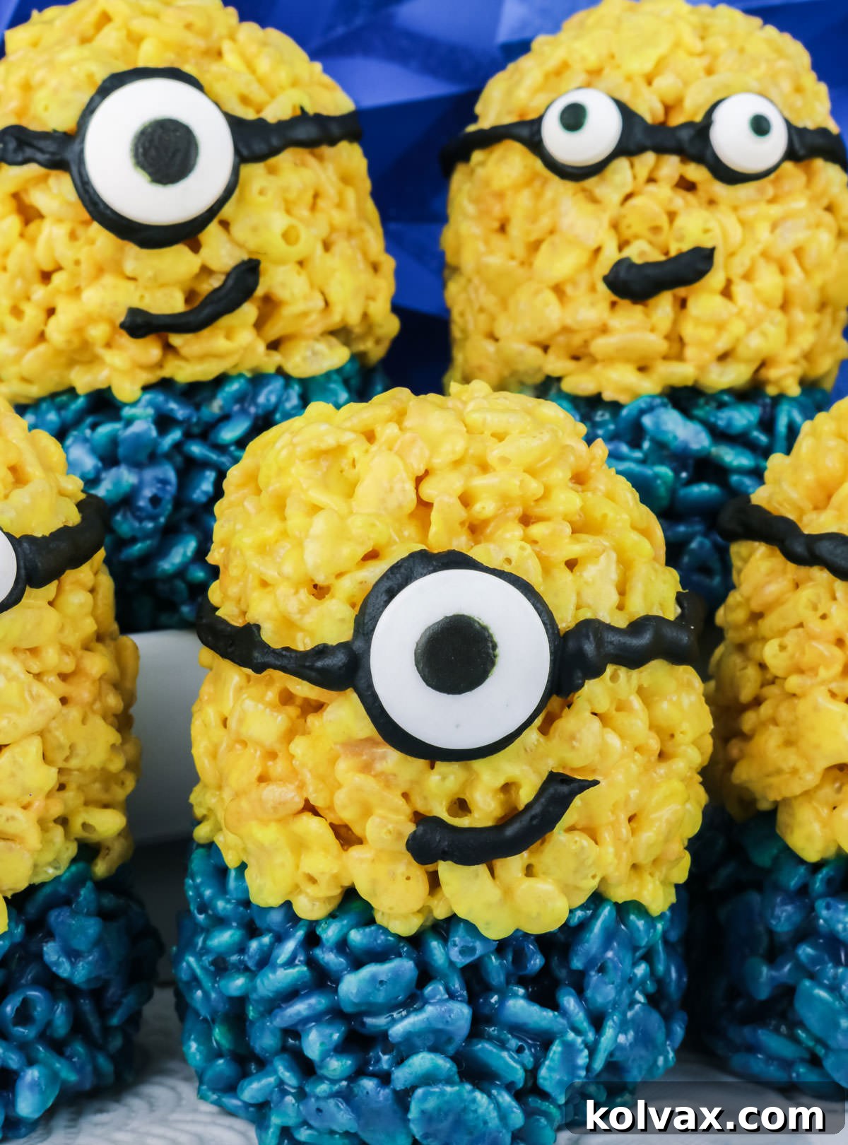Five finished Minions Rice Krispie Treats on a white surface with a blue background, showcasing their fun details.