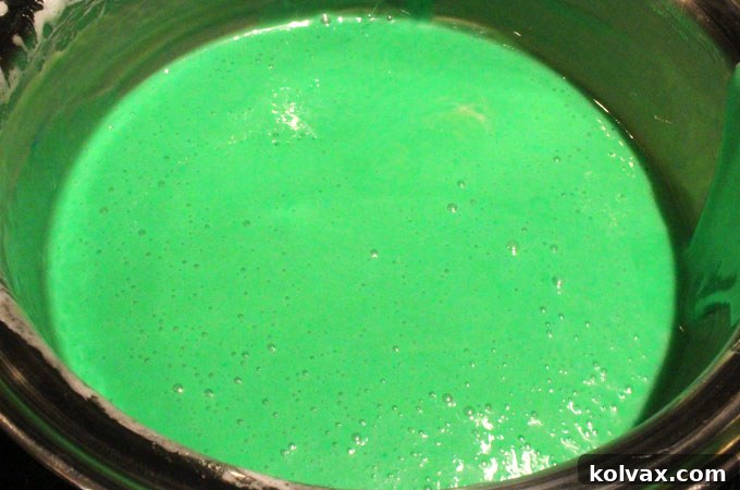 Tinting the marshmallow mixture with green food coloring.