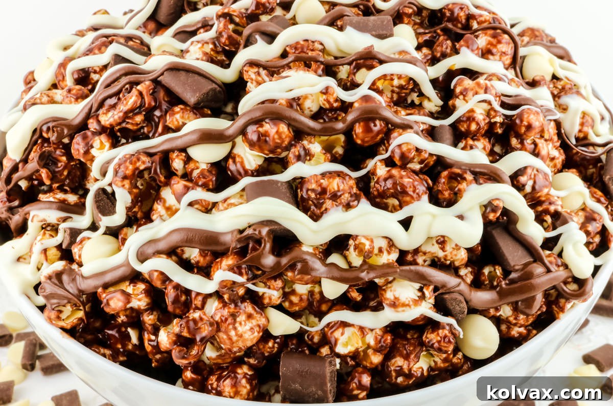Decadent Pop 2 Closeup on a white serving bowl filled with chocolate popcorn, studded with pieces of dark and white chocolate, ready to be enjoyed.