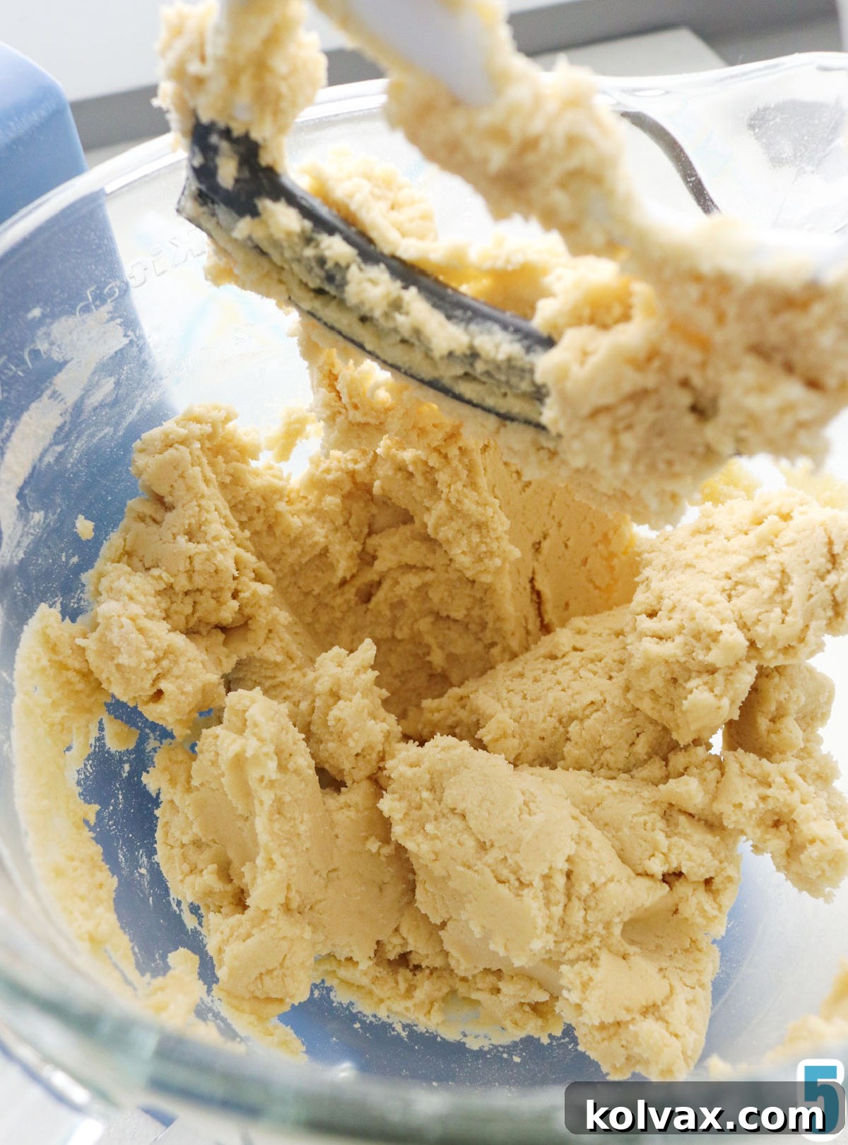Melt-in-Your-Mouth Snickerdoodle Perfection 4 Closeup up on the Snickerdoodle cookie dough in a glass mixing bowl with a mixing paddle showing at the top.