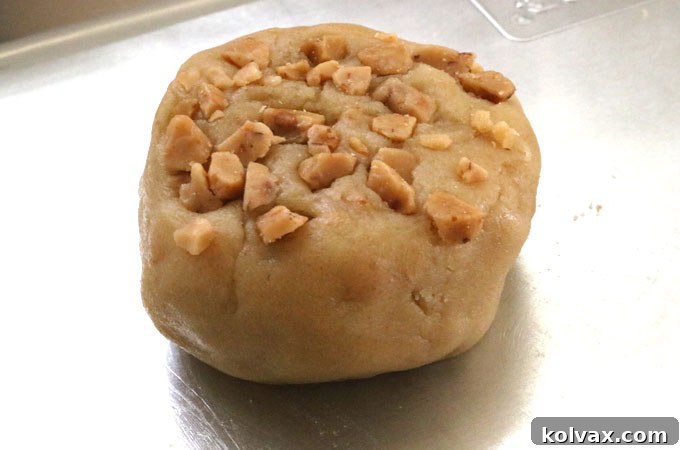 Toffee Chip Cookie dough balls, each with extra toffee bits pressed on top, arranged on a baking sheet.