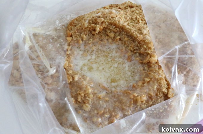 Pouring a stream of golden melted butter into the plastic bag containing the mixed graham cracker crumbs and sugar.