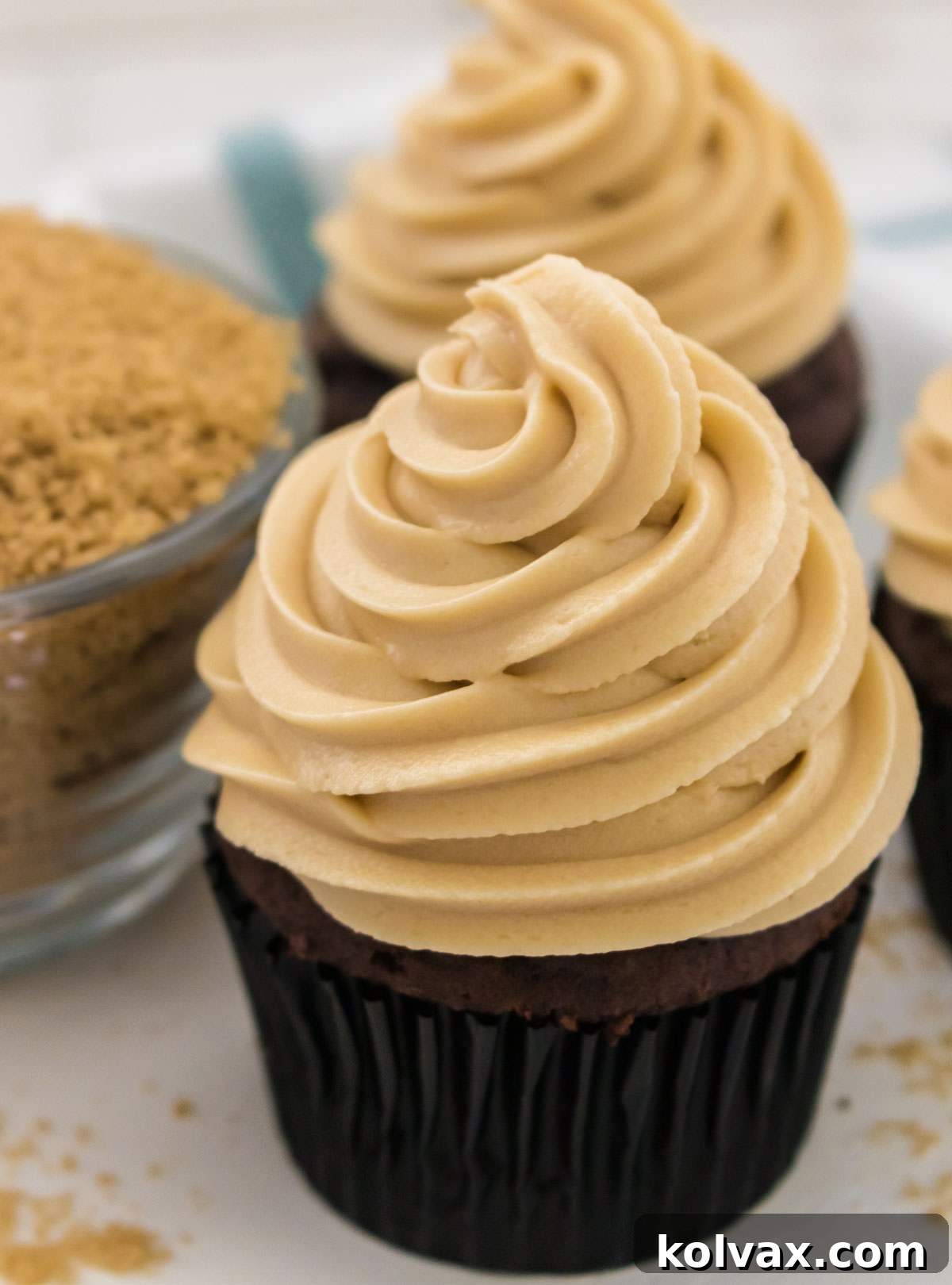 Heavenly Brown Sugar Cream Cheese Frosting 6 Close-up of a single chocolate cupcake lavishly topped with The Best Brown Sugar Cream Cheese Frosting, artfully placed beside a small bowl of brown sugar for visual appeal.