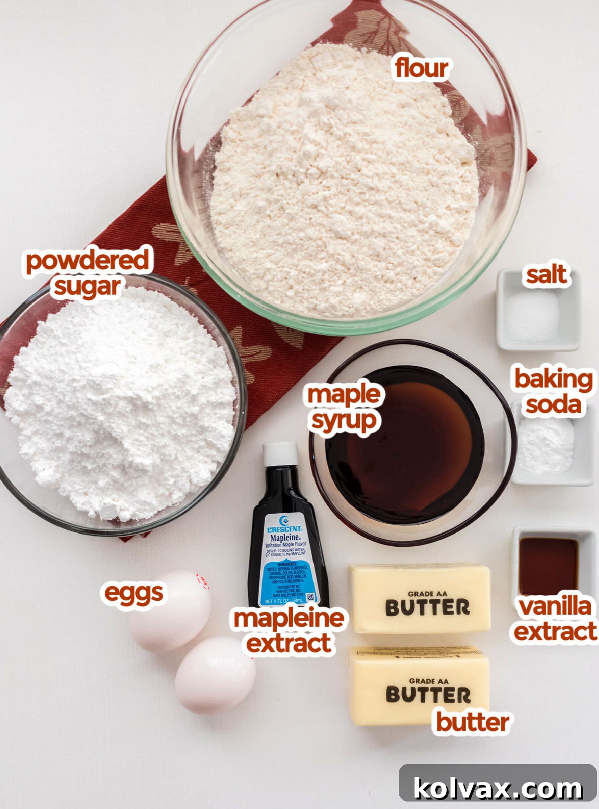 A vibrant flat lay showcasing all the fresh ingredients required to bake delectable Maple Cookies with Maple Icing. Key components include all-purpose flour, fine salt, baking soda, rich pure maple syrup, powdered sugar, farm-fresh eggs, fragrant vanilla extract, authentic maple extract or Mapleine, and creamy unsalted butter.