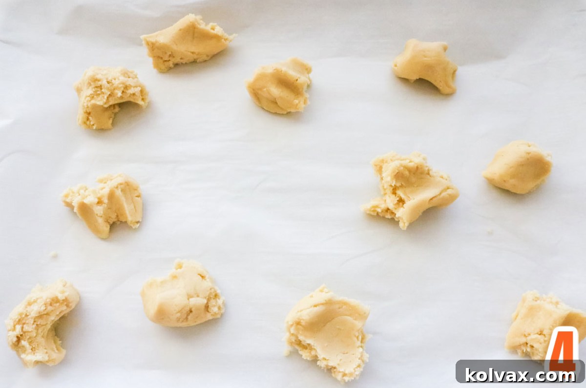 Marbled Harvest Sugar Cookie Bars 5 Small pieces of white sugar cookie bar dough scattered randomly on a parchment-lined cookie sheet, forming the base of the marble pattern.