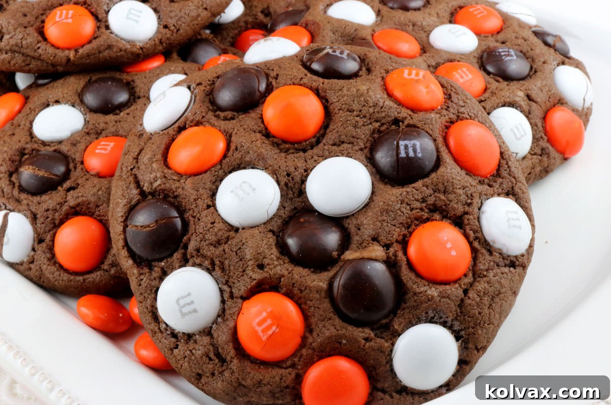 Closeup of a white serving plate filled with festive Halloween M&M Cookies, showcasing their vibrant colors.