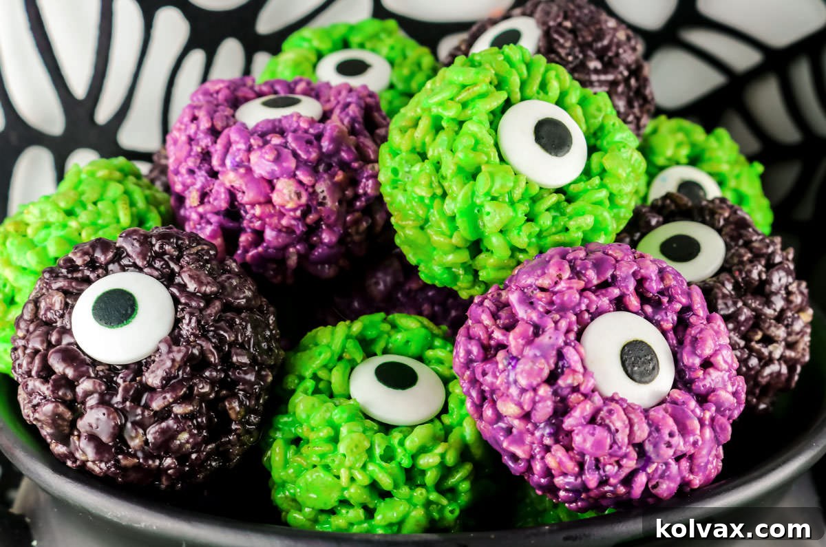 Close-up of a stack of Halloween Monster Eye Balls Rice Krispie Treat Bites arranged in front of a decorative black spider web.