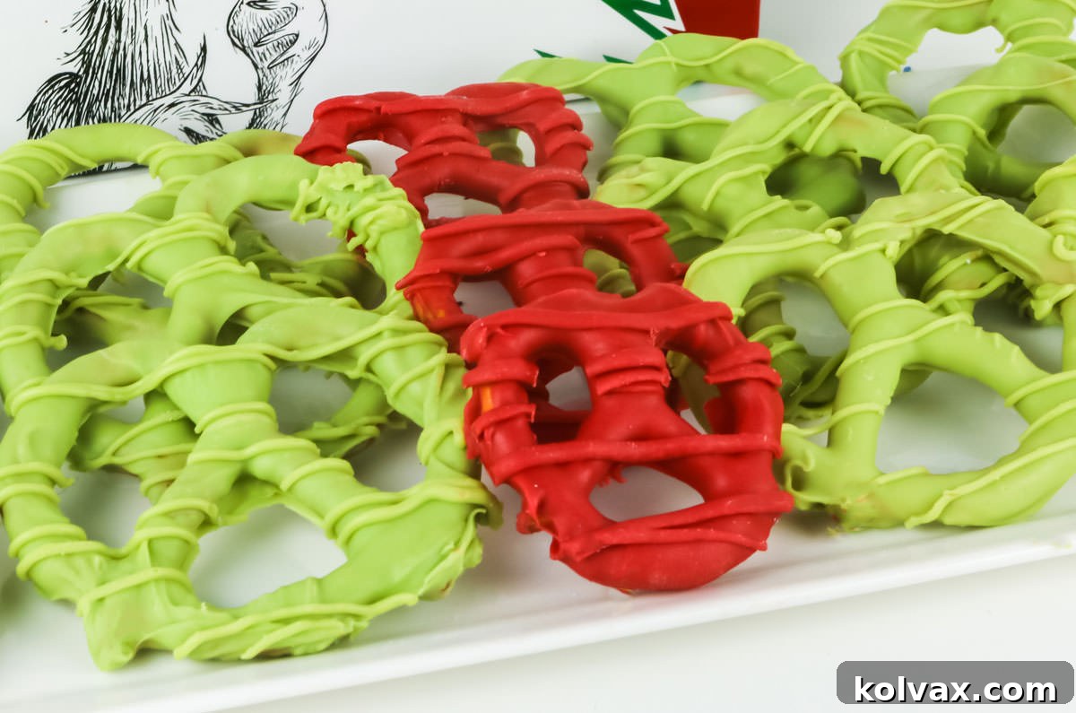 Grinch Heart Pretzels arranged in rows on a white serving dish in front of a copy of the How the Grinch Stole Christmas book.