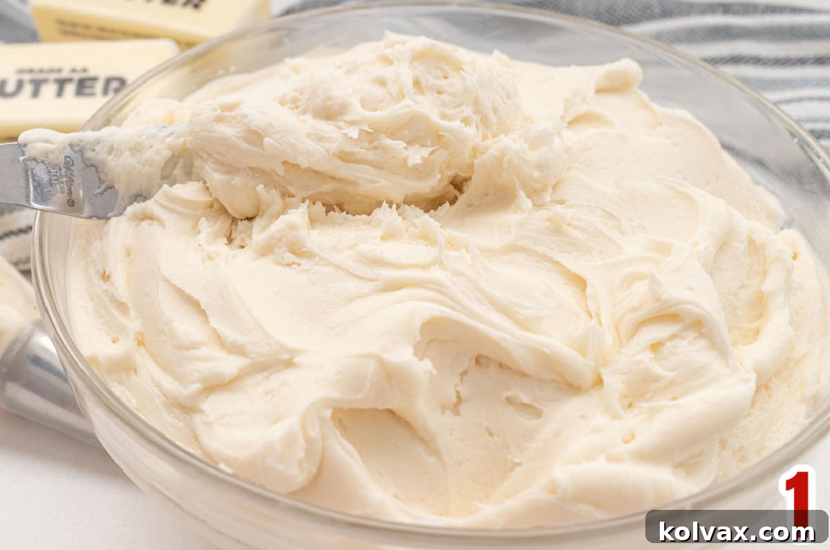 Closeup on a clear glass bowl filled with freshly made homemade buttercream frosting, looking smooth and creamy, ready to be colored for festive decorations.