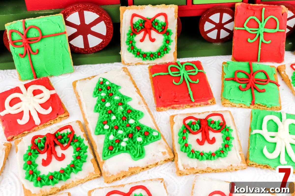 A stunning collection of frosted graham crackers showcasing a variety of intricate Christmas designs, including detailed wreaths with red bows and sparkling Christmas trees, elegantly arranged on a white table, ready for a festive display.