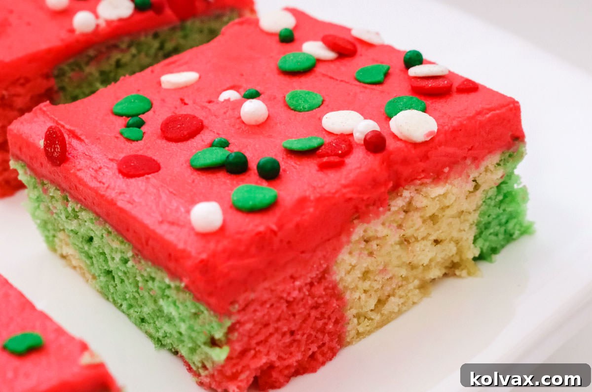 Closeup on an individual piece of Christmas Marble Sugar Cookie Bar sitting on a white serving platter, showcasing its vibrant marbled layers and smooth red frosting.