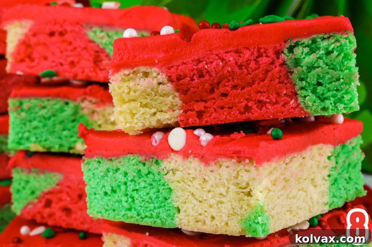 Closeup on a freshly frosted batch of Christmas Marble Sugar Cookie Bars, artfully cut into squares and stacked in groups of three, showcasing their unique marbled patterns.