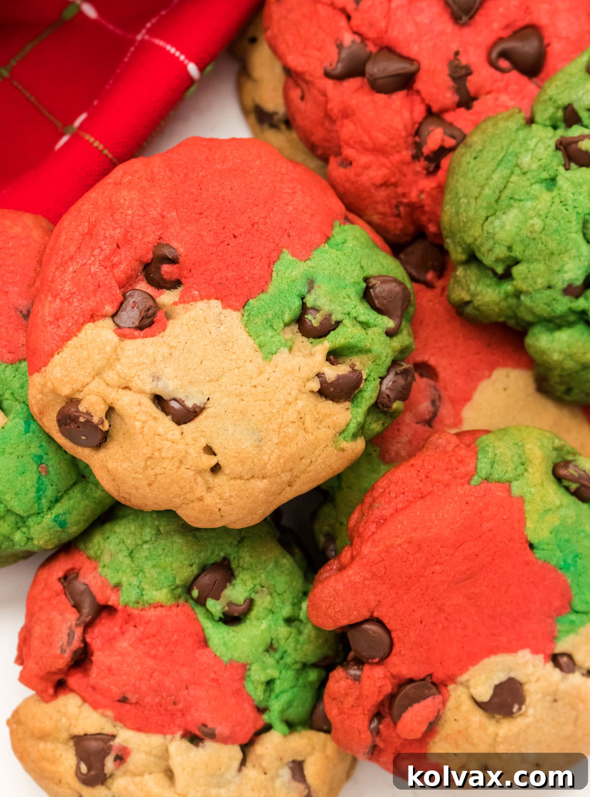 Red and Green Christmas Chocolate Chip Cookies stacked on a white table.