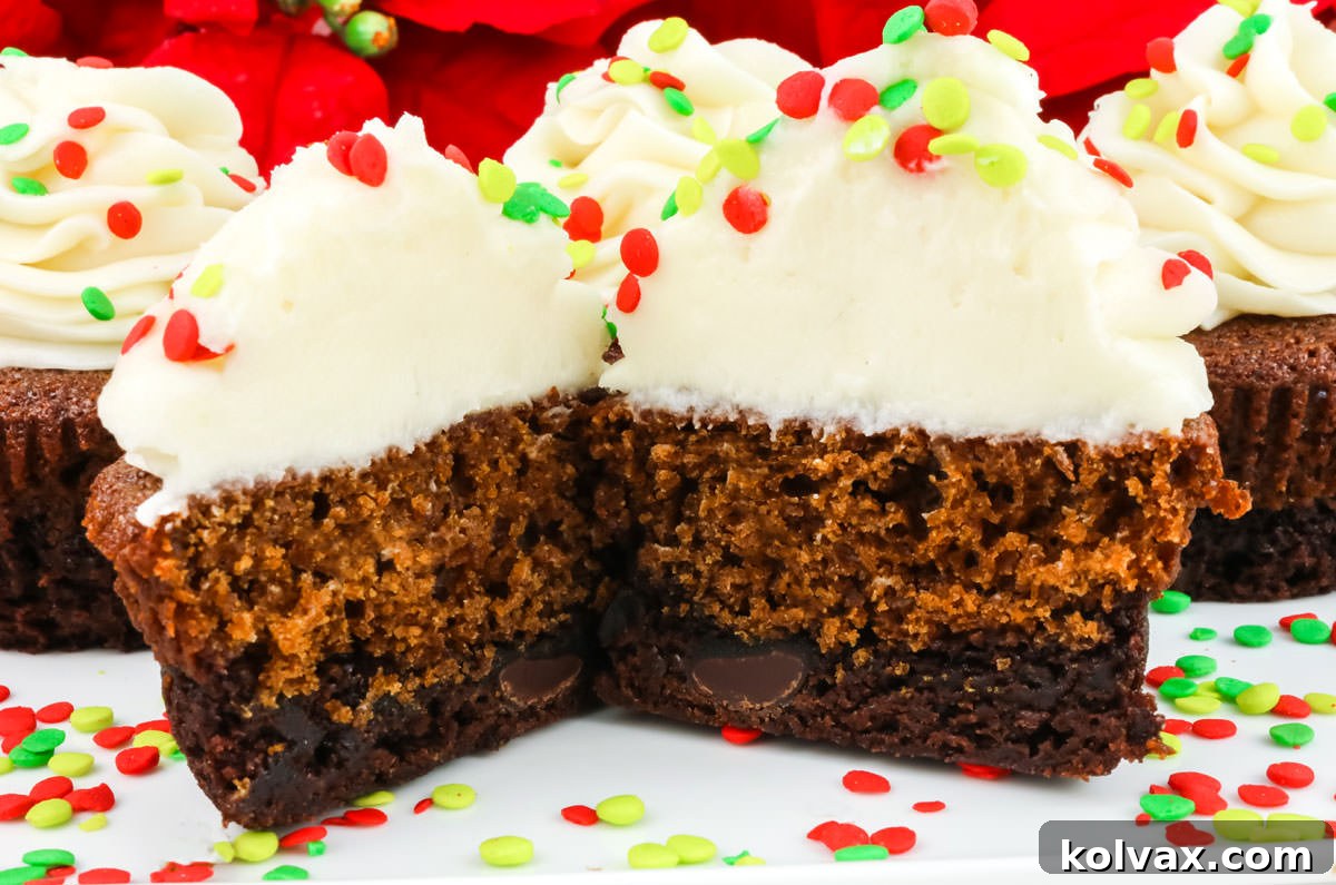 Closeup of beautifully decorated Brownie Gingerbread Cupcakes, one cut in half revealing distinct layers of rich brownie and spiced gingerbread cake, topped with creamy white buttercream frosting and festive sprinkles, perfect for Christmas celebrations.