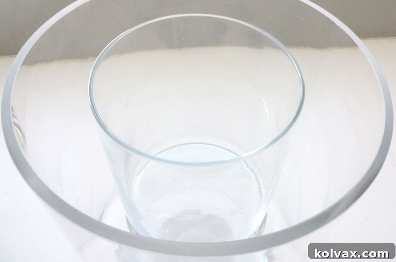 Setting up the vases: a smaller cylinder vase placed inside a larger hurricane vase, ready for candy and floral arrangement.