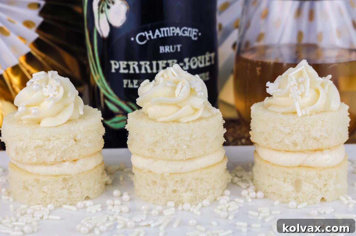 Closeup on three Champagne Cake Bites sitting on a white plate surrounded by white sprinkles, a bottle of champagne and a glass of champagne.