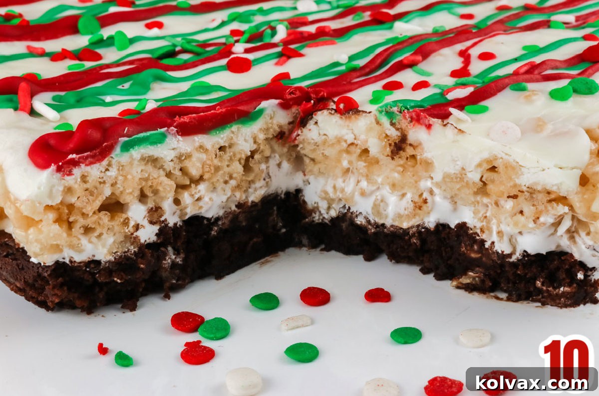 A close-up of a batch of perfectly cut Christmas Brownie Rice Krispie Treats resting on a pristine white surface, with one treat carefully removed, showcasing its delicious, distinct layers.