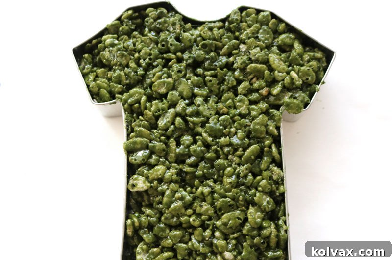 Molding the green Rice Krispie Treat mixture into a football jersey shape.