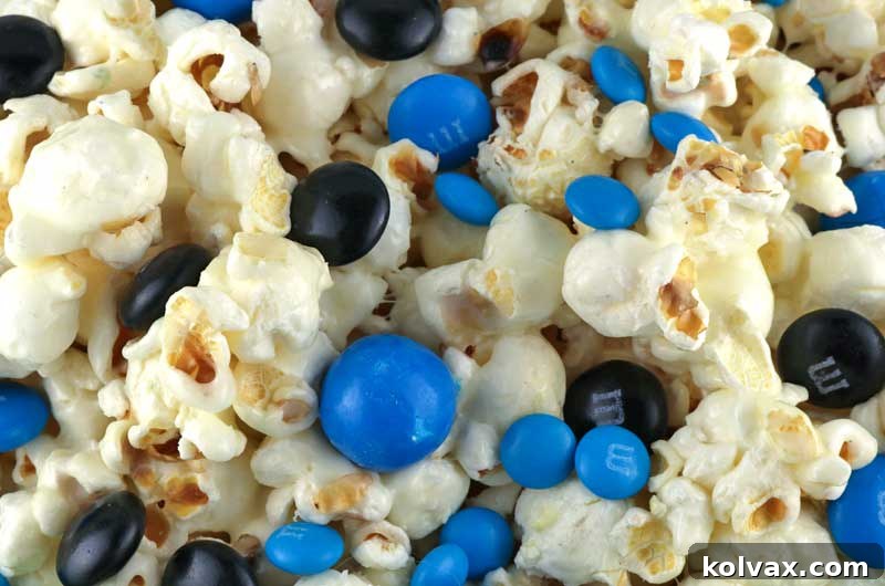 Finished Jacksonville Jaguars popcorn, brightly colored with blue and black M&Ms, cooling on a baking sheet, ready to be broken apart and served at a football party.
