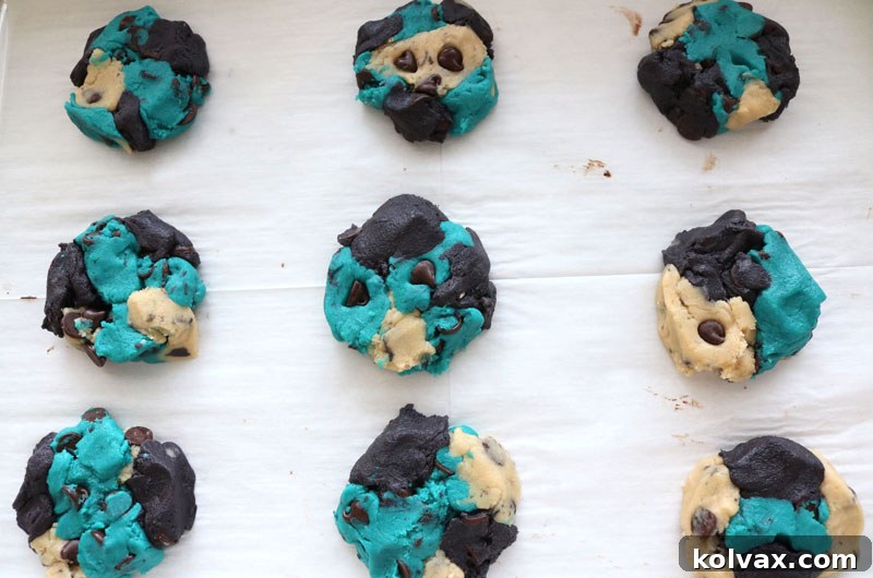 Marbled Jacksonville Jaguars chocolate chip cookie dough balls placed on a baking sheet, slightly pressed down and ready for the oven to bake.