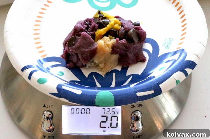 Various pieces of purple, gold, and white cookie dough being weighed to form a 2.0 oz marbled cookie ball.