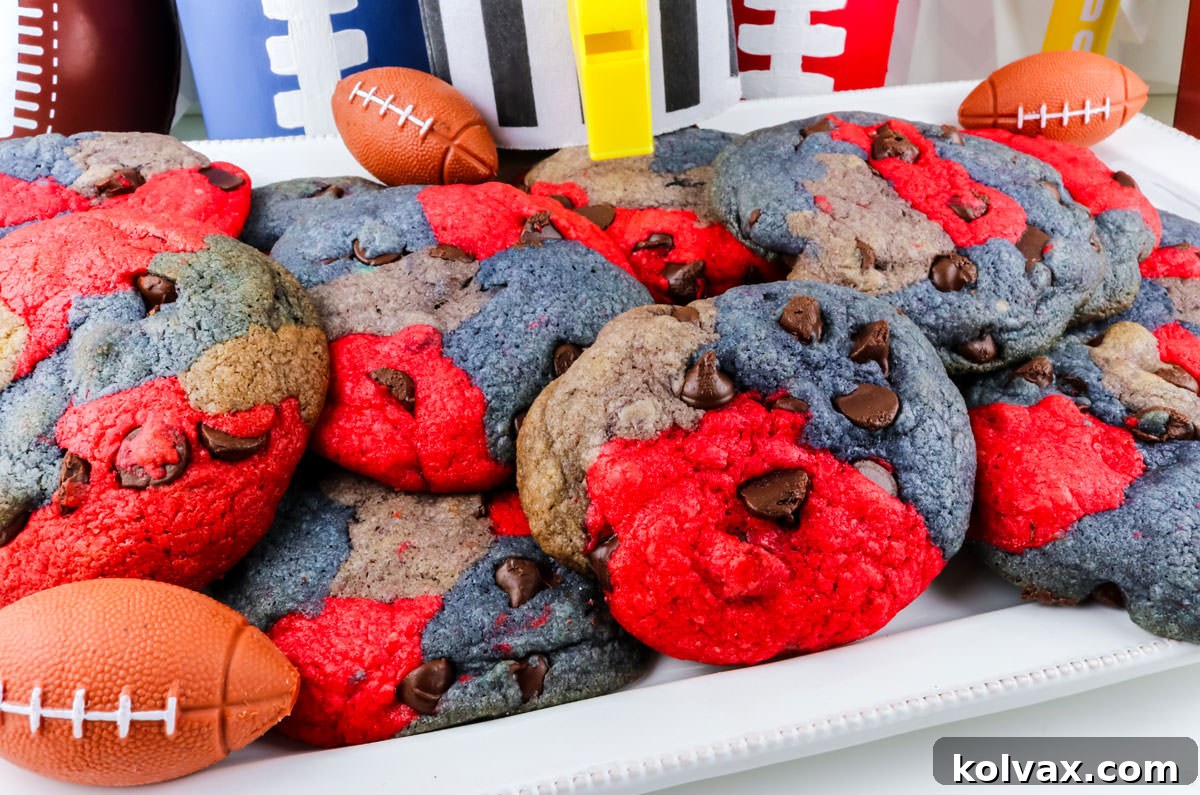 Closeup on a white dessert platter filled with a batch of New England Patriots Chocolate Chip Cookies, featuring red, navy, and grey marble swirls.