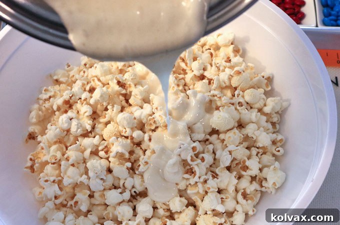 Pouring melted marshmallow mixture over salted popcorn