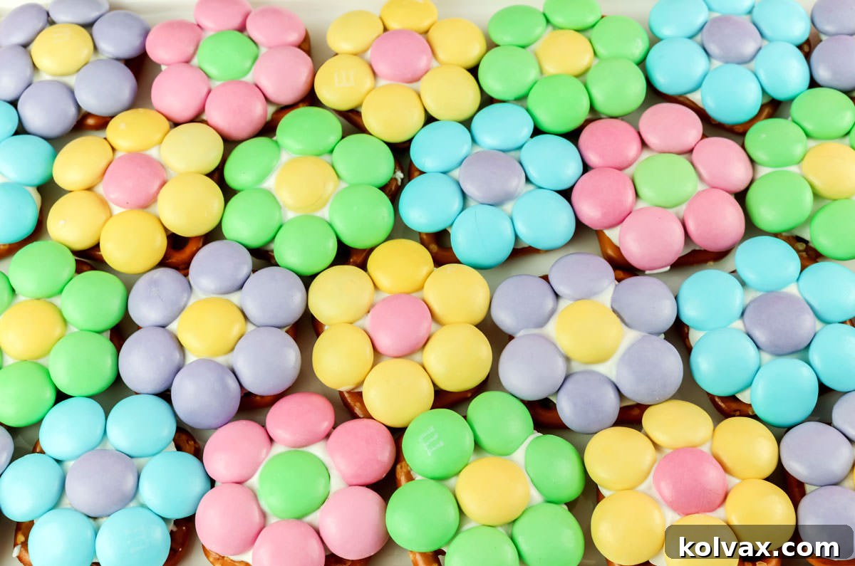 Closeup on twenty Spring Flower Pretzel Bites laying on a white surface with soft pastel colors.