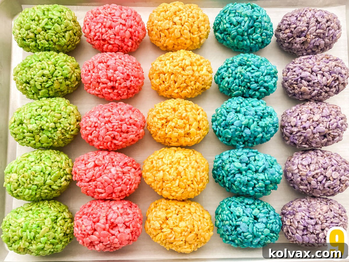 Closeup on a cookie sheet filled with neat rows of green, pink, yellow, blue and purple Rice Krispie Easter Eggs, ready for cooling.