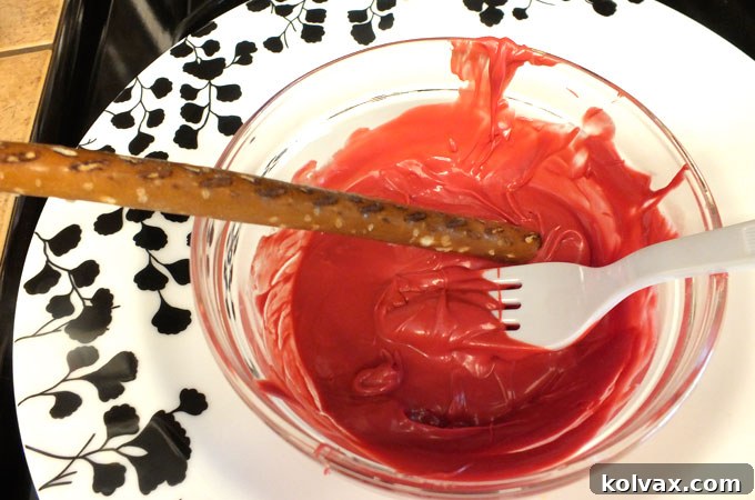 Adding melted candy to the pretzel rod to create the lightsaber blade effect