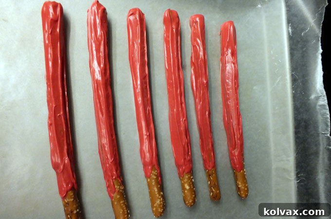 Lightsaber pretzels resting on wax paper to set, showcasing the vibrant colors