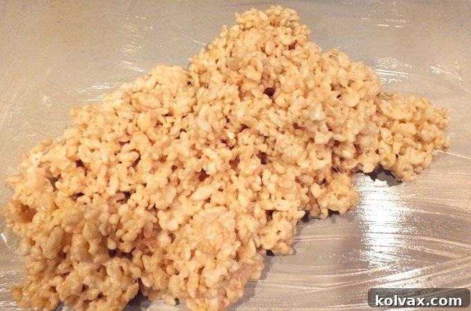 Rice Krispie mixture being poured onto a greased cookie sheet