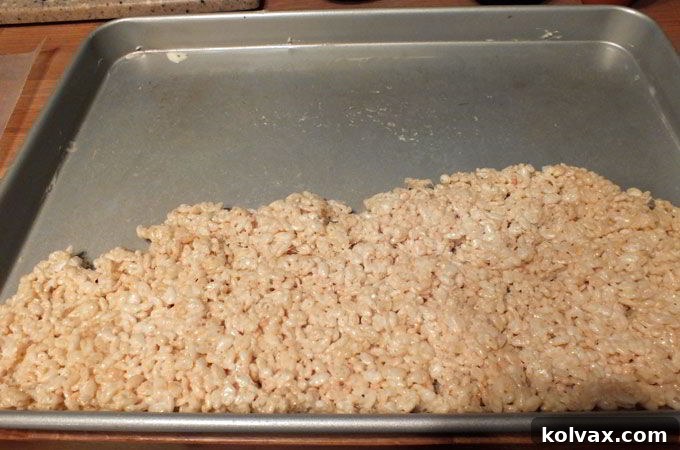 Hands pressing together Rice Krispie treat remnants to cut more shapes