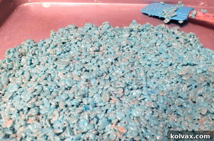 A batch of blue-colored Rice Krispie treats spread on a baking sheet, ready for cutting
