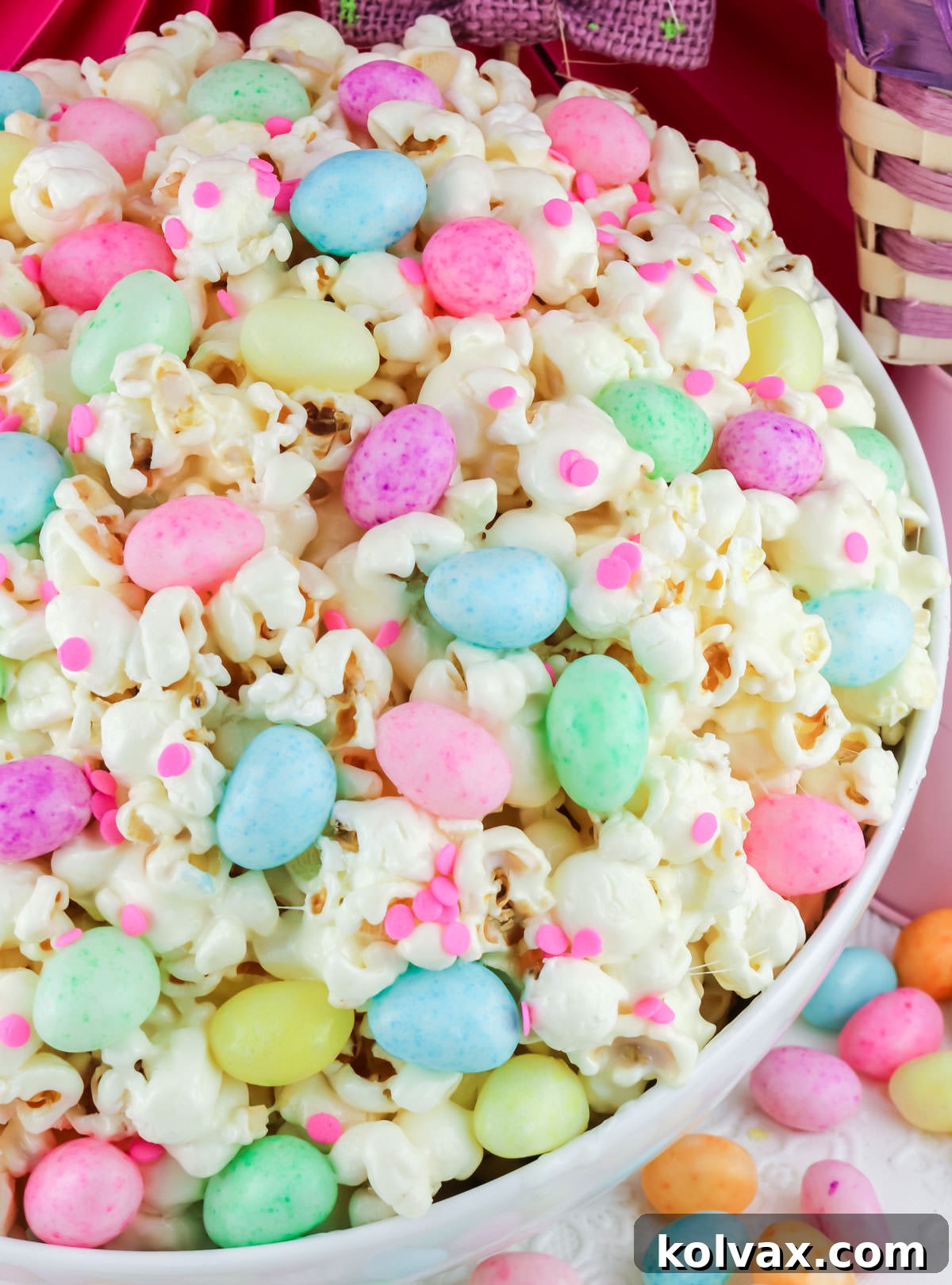 A beautiful close-up of a large white serving bowl brimming with Easter Jelly Bean Popcorn, surrounded by scattered speckled Easter jelly beans, creating an inviting and festive display.