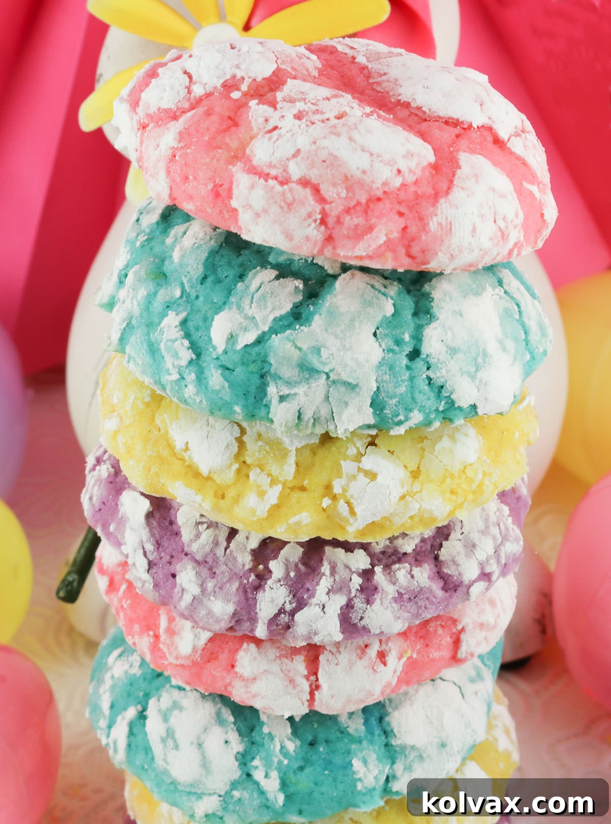 A vibrant close-up of a tall stack of beautifully colored Lemon Crinkle Cookies, showcasing the pink, blue, yellow, and purple pastels and their delightful crinkled texture.