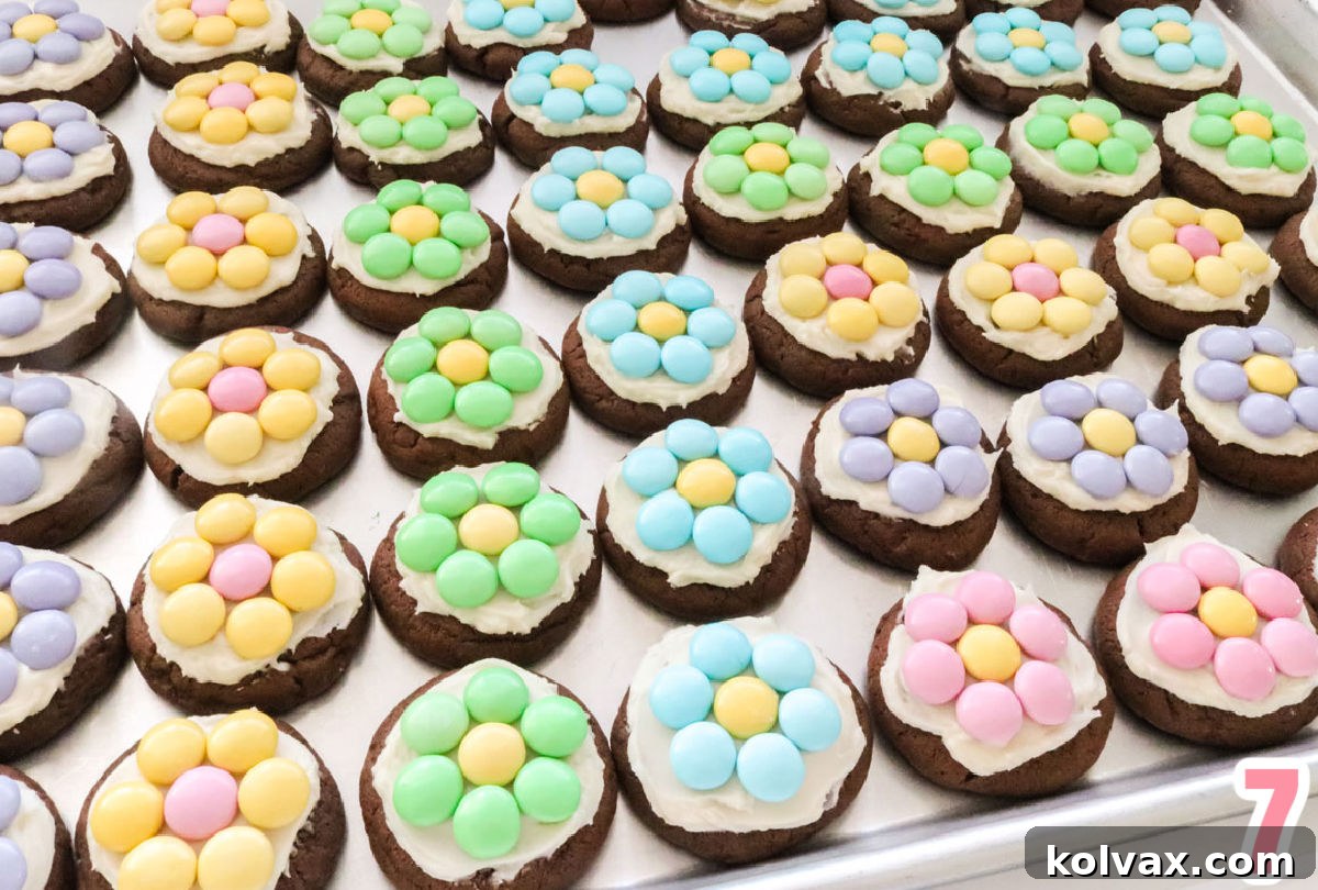 M&M Flower Chocolate Cookies perfectly lined up in neat rows across a gleaming silver cookie sheet, showcasing their colorful appeal.